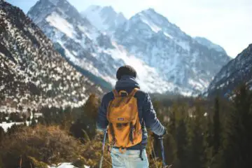 Man hiking on a mountain with a backpack and hiking sticks