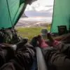 Two campers sleeping iside a tent and laying on an air mattress