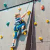 Young 7-year-old kid climbing up a bouldering wall